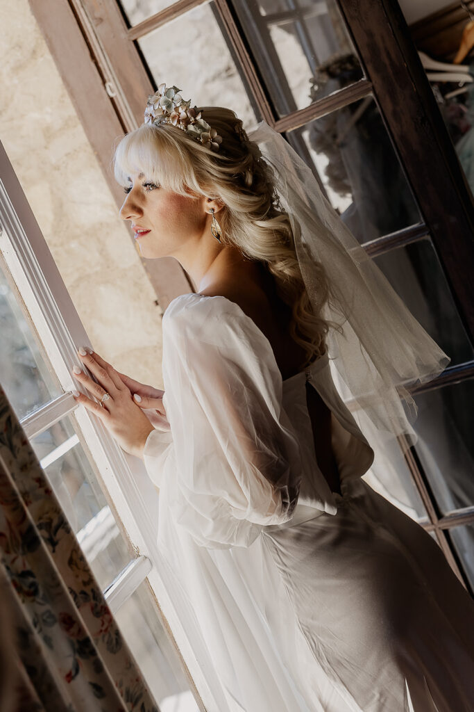 Bride looking out the window of La Baronia in Barcelona Spain.
