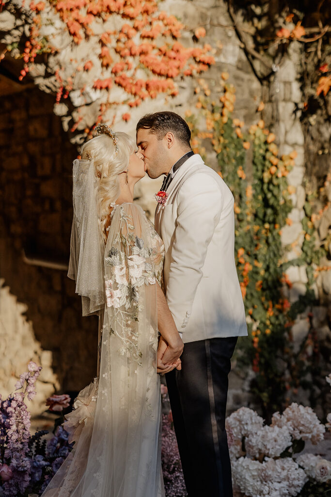 Bride and groom sharing their first kiss during their outdoor wedding ceremony.