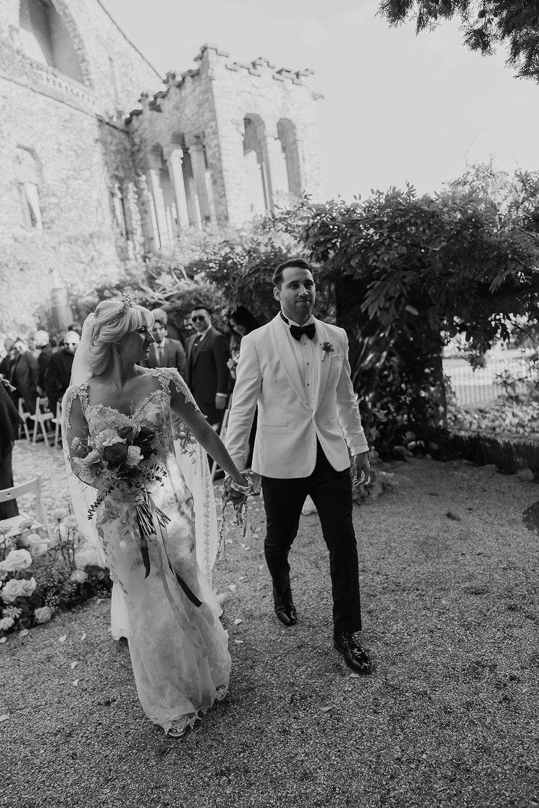 Black and white photo of a bride and groom walking down the aisle after their ceremony at La Baronia wedding venue in Barcelona Spain.