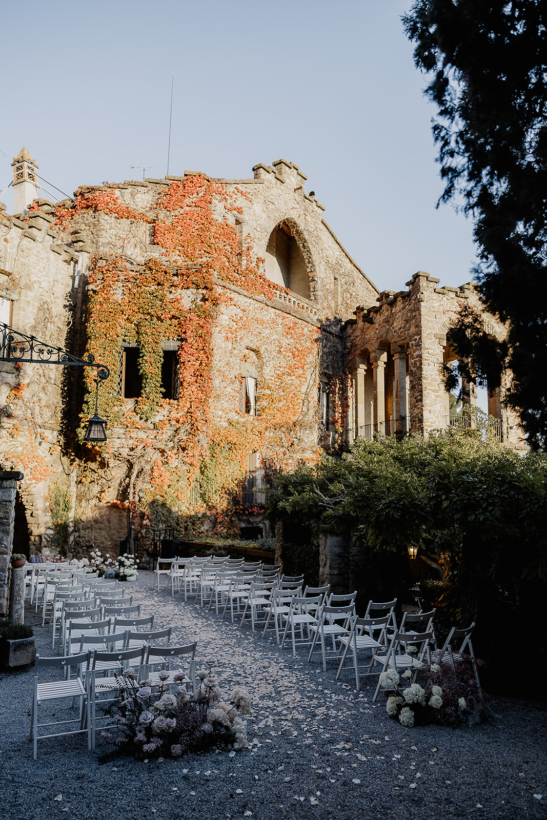 Outdoor wedding ceremony setup at the Cabañon at La Baronia wedding venue with white chairs and ivy covered historic stone architecture in Barcelona Spain