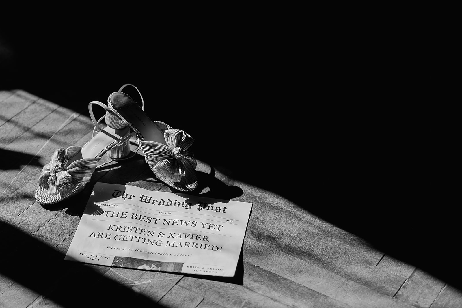 Black and white detail shot of the brides heels styled next to a wedding newspaper. 