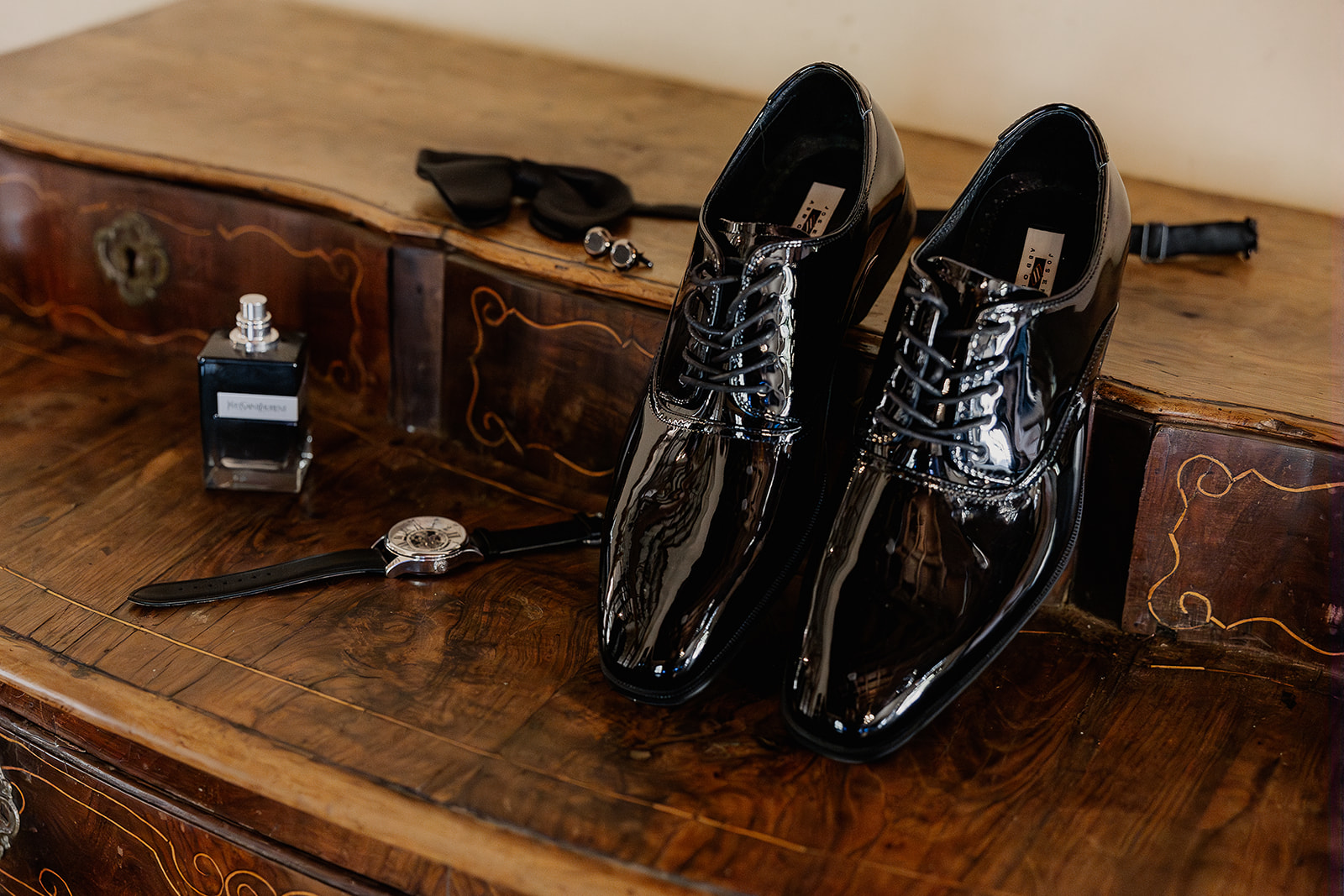 Close up shot of grooms wedding details rested on a wooden dresser inside of La Baronia in Barcelona Spain.