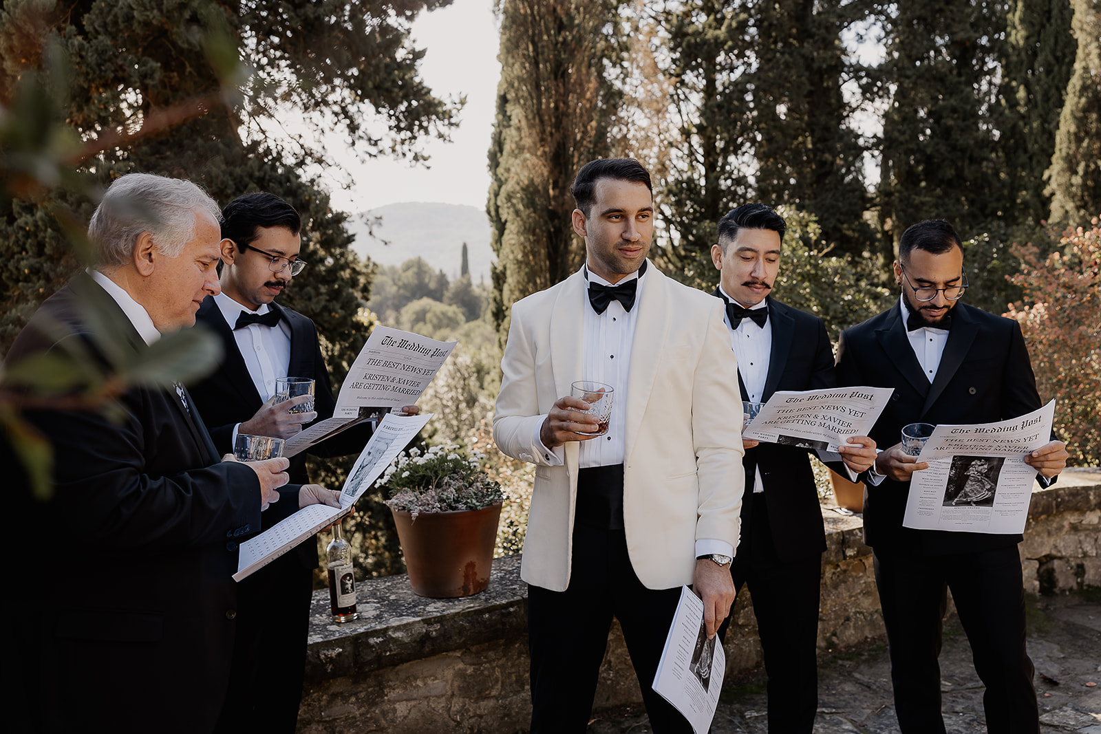 Groom and groomsmen reading wedding newspapers together before the ceremony at a La Baronia wedding in Barcelona Spain.