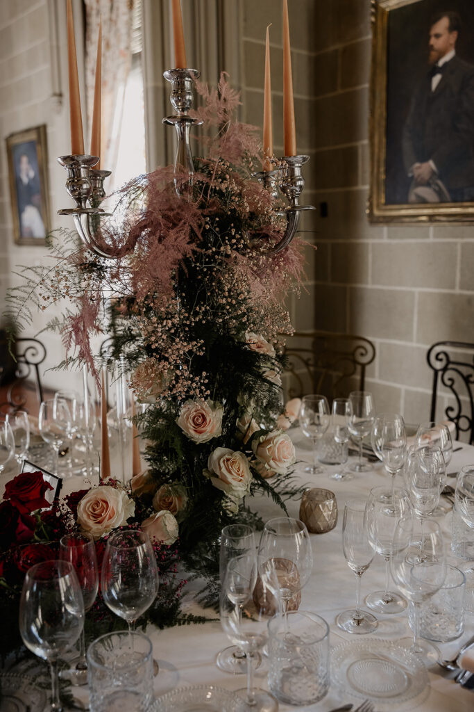 Reception table decor with tall floral centerpiece and candles inside indoor lounge at La Baronia wedding venue in Barcelona Spain