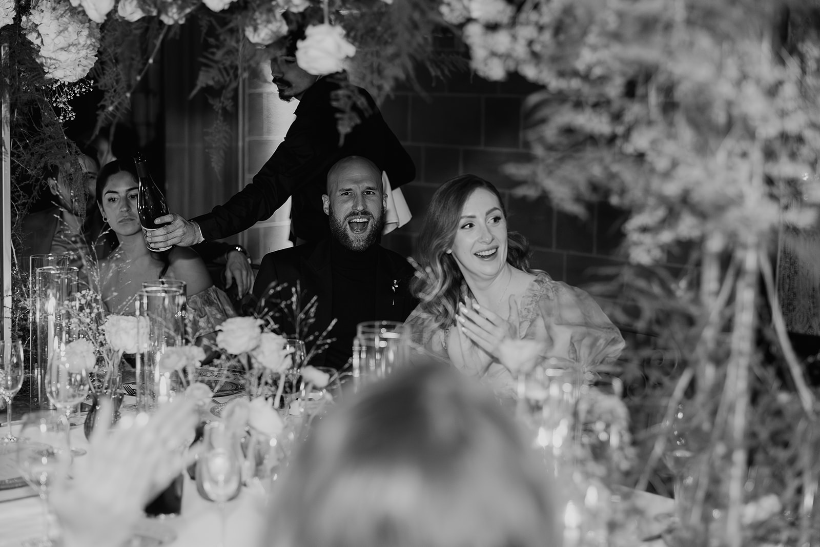 Black and white candid wedding reception photo of guests surprised during reception activities. 