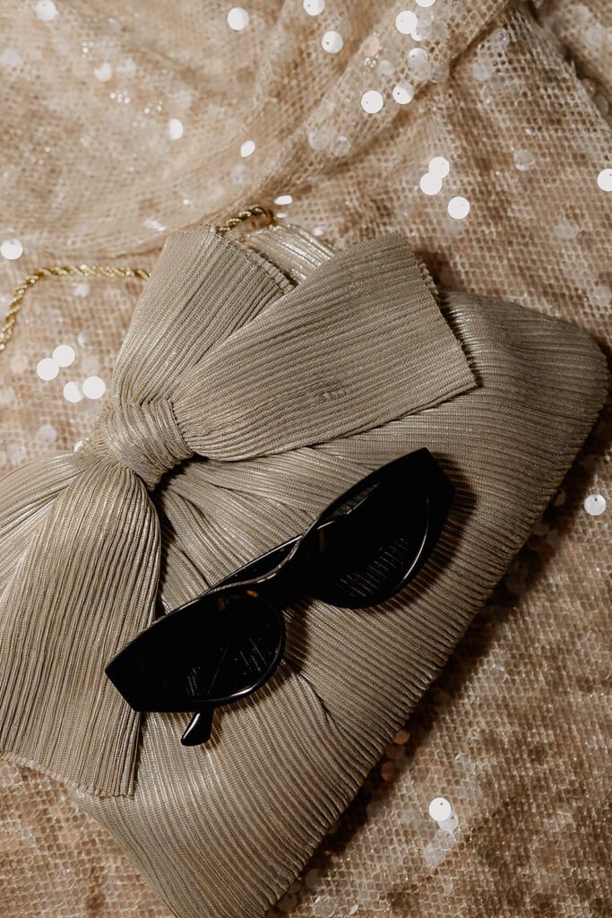 Brides gold wedding reception dress change with purse and sunglasses.