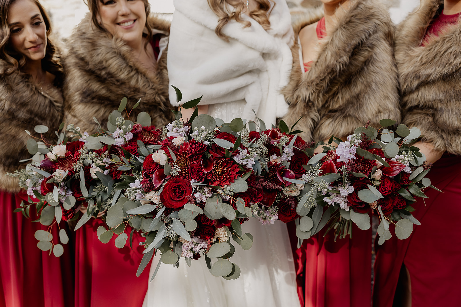 Bridal party holding bouquets with red florals during portraits at The Farmhouse wedding venue in Hampton, NJ.