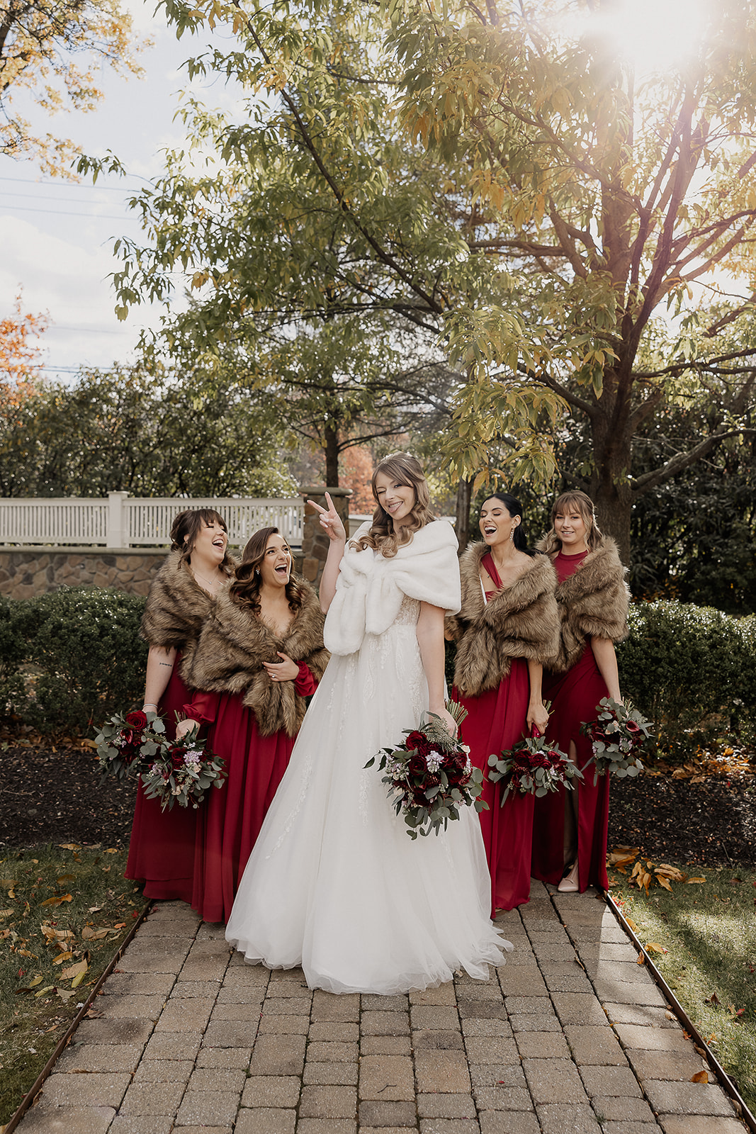 Bride smiling with bridesmaids in red dresses during portraits at The Farmhouse wedding venue in Hampton, NJ.