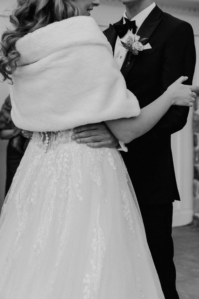 Close up black and white photo of a bride and groom holding each other.