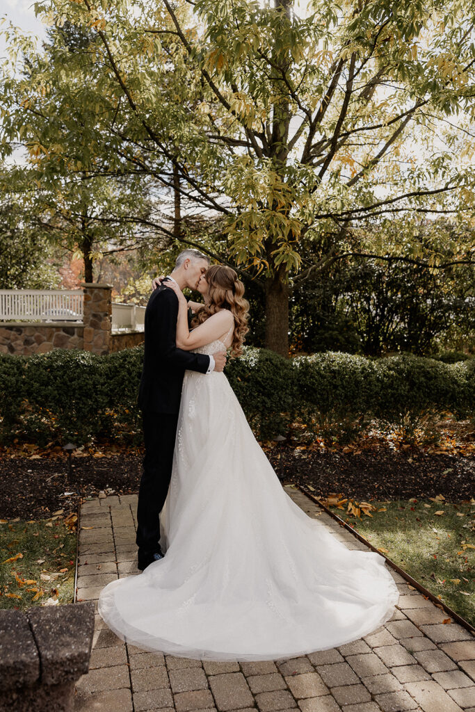 Bride and groom kissing in garden during portraits at The Farmhouse wedding venue in Hampton, NJ.