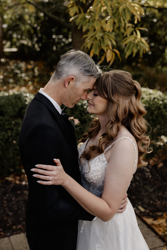 Bride and groom standing close together in garden during portraits at The Farmhouse wedding venue in Hampton, NJ.