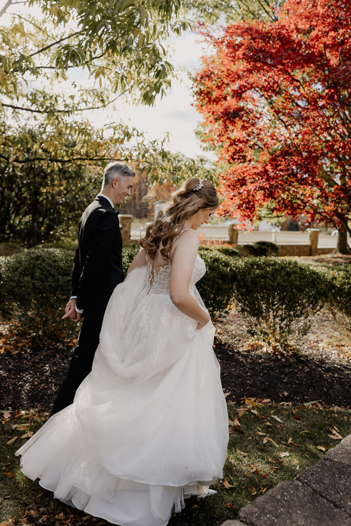 Bride and groom walking the grounds of the venue during their fall wedding portraits.