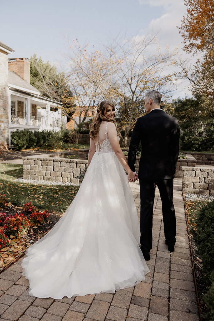 Bride and groom walking hand in hand on stone path during portraits at The Farmhouse wedding venue in Hampton, NJ.