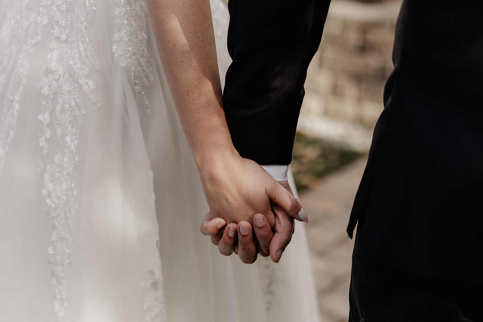 Close up shot of the bride and groom holding hands as they walk the venue grounds.