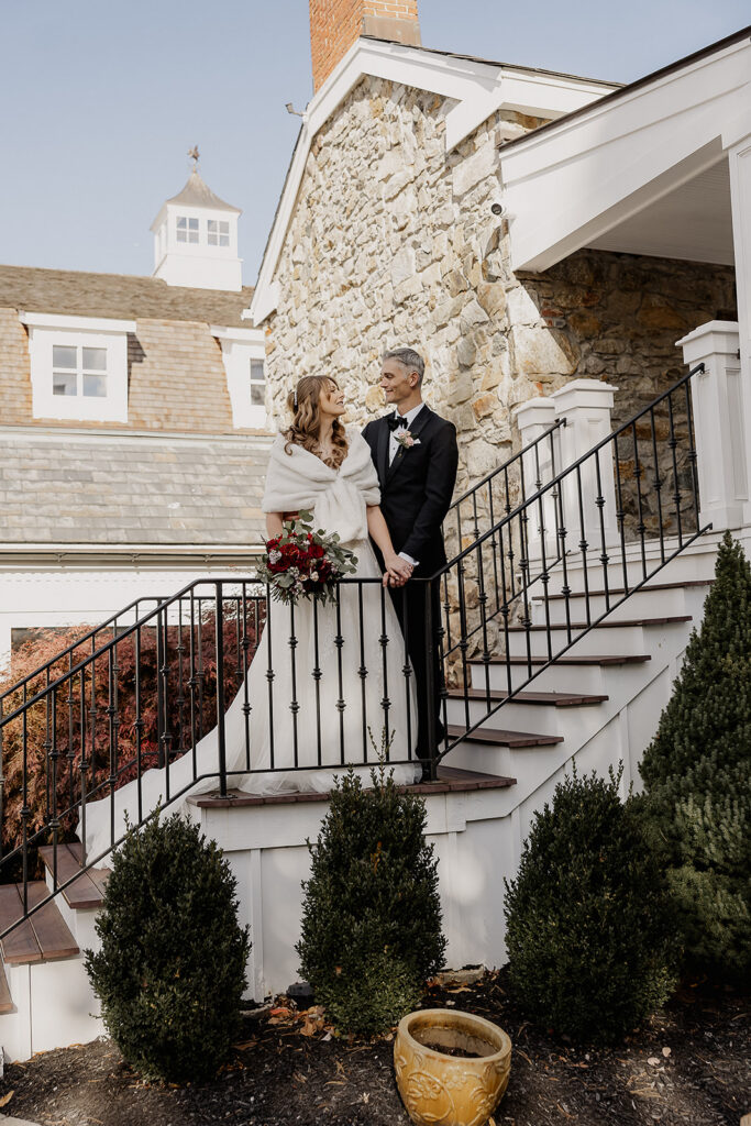 Bride and groom standing on steps outside venue building during portraits at The Farmhouse wedding venue in Hampton, NJ.