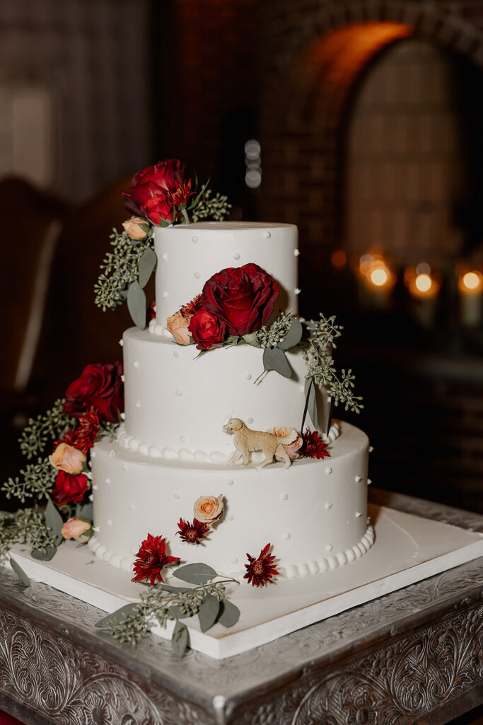 Three tier wedding cake with red florals and dog topper at The Farmhouse wedding venue in Hampton, NJ.