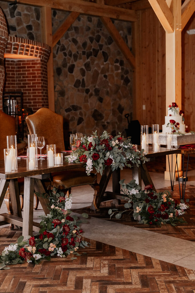 Head table with candles, florals, and fireplace backdrop at The Farmhouse wedding venue in Hampton, NJ.