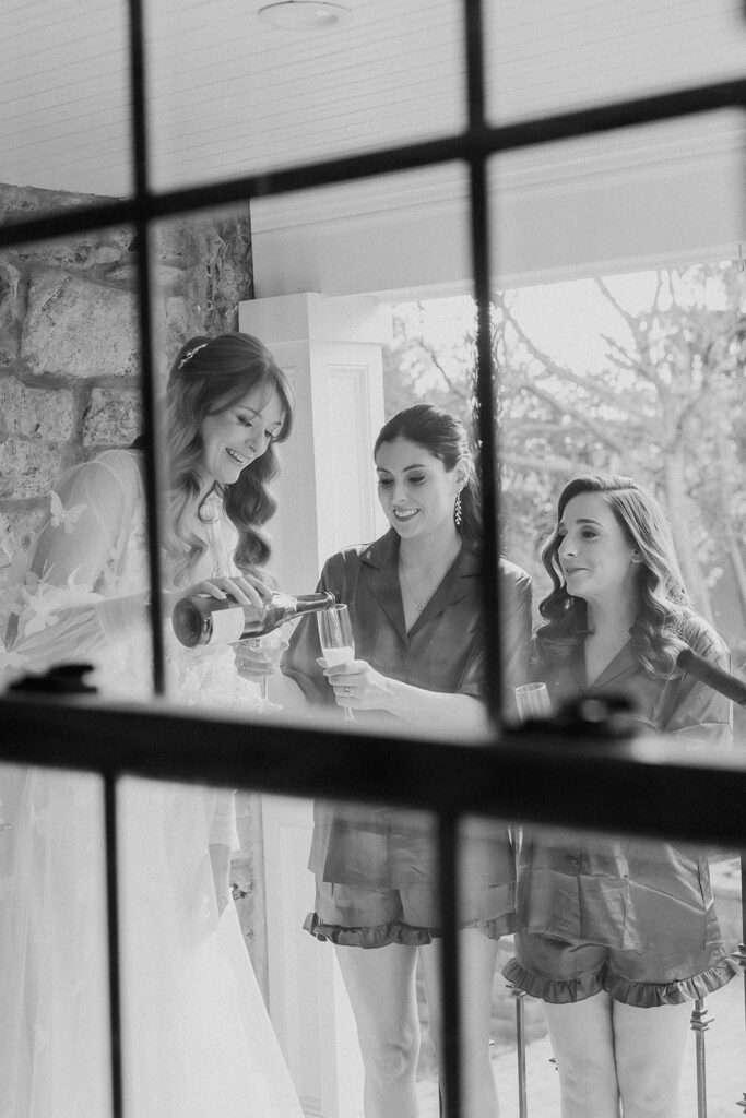 Bride and bridesmaids toasting with champagne during getting ready at a farmhouse wedding in Hampton, NJ.