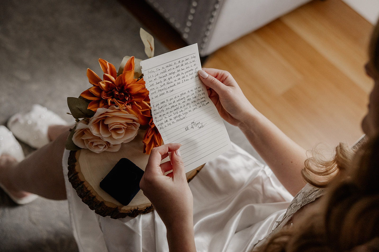 Close up photo of a bride reading a letter as she gets ready.