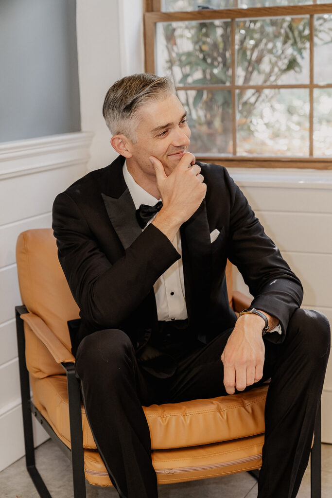 Groom sitting and getting ready with relaxed posture at a farmhouse wedding in Hampton, NJ.