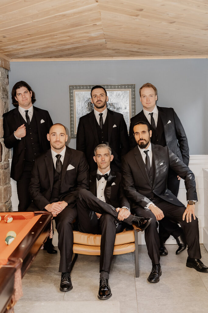 Groom and groomsmen posing together indoors at a farmhouse wedding in Hampton, NJ.