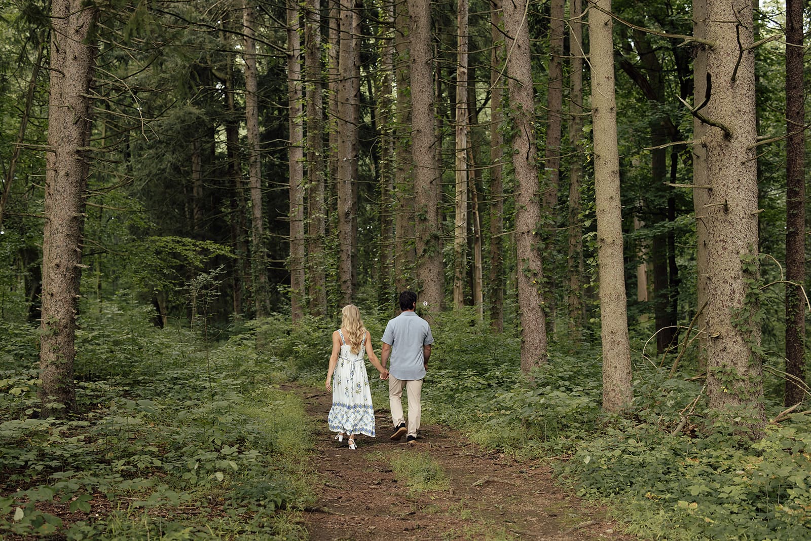 Couple walking along a wooded path for their NJ engagement photos at Cross Estate Gardens.