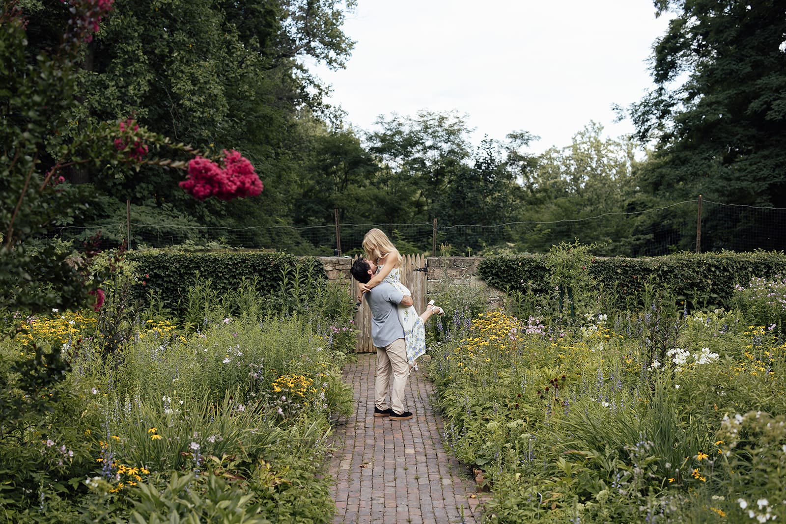 Man lifting his fiancé on the gardens at Cross Estate Gardens during their engagement photos.