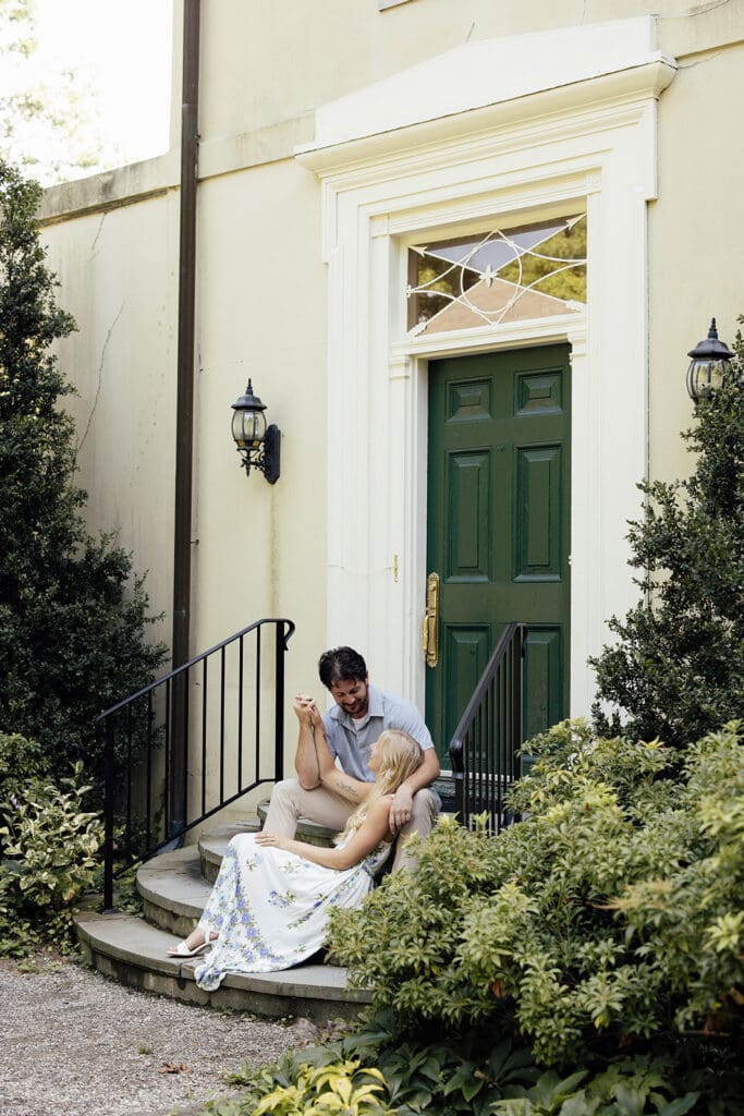 Couple sitting on the steps of a building for their NJ engagement photos at Cross Estate Gardens.