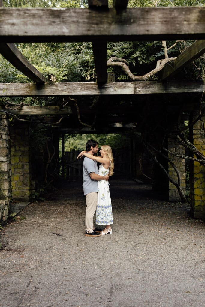 Couple standing under a pergola for their Cross Estate Gardens engagement photos.