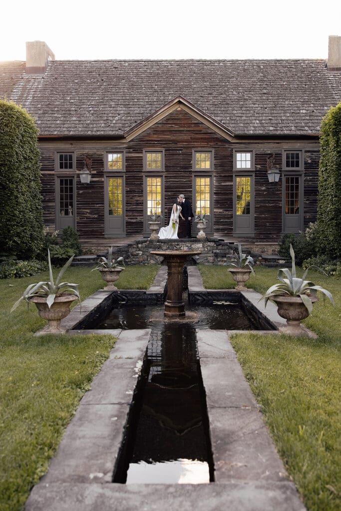 Couple kissing in front of a building at Jardin de Buis in New Jersey.