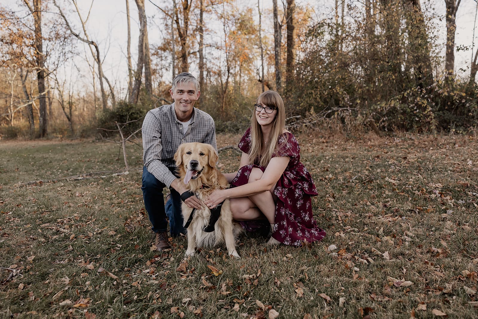Couple posing in an open grassy area with their dog for their engagement photos at at Jockey Hollow in Morristown, NJ.