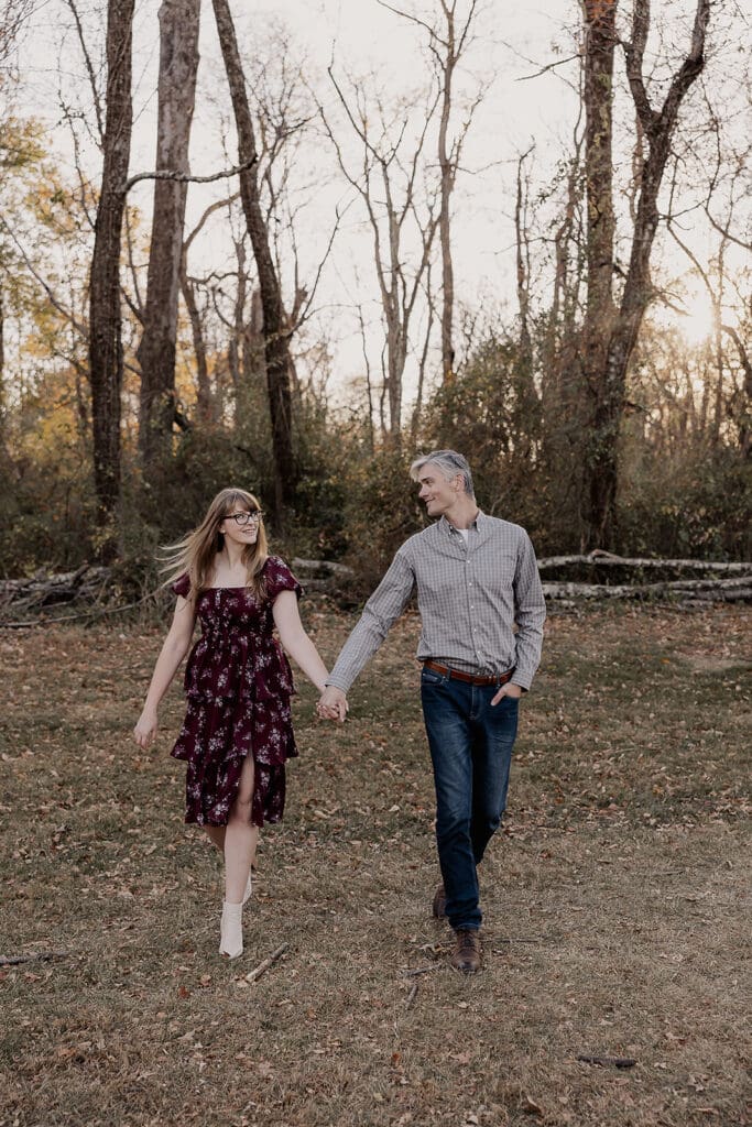 Couple holding hands and walking during golden hour at at Jockey Hollow in Morristown, NJ.