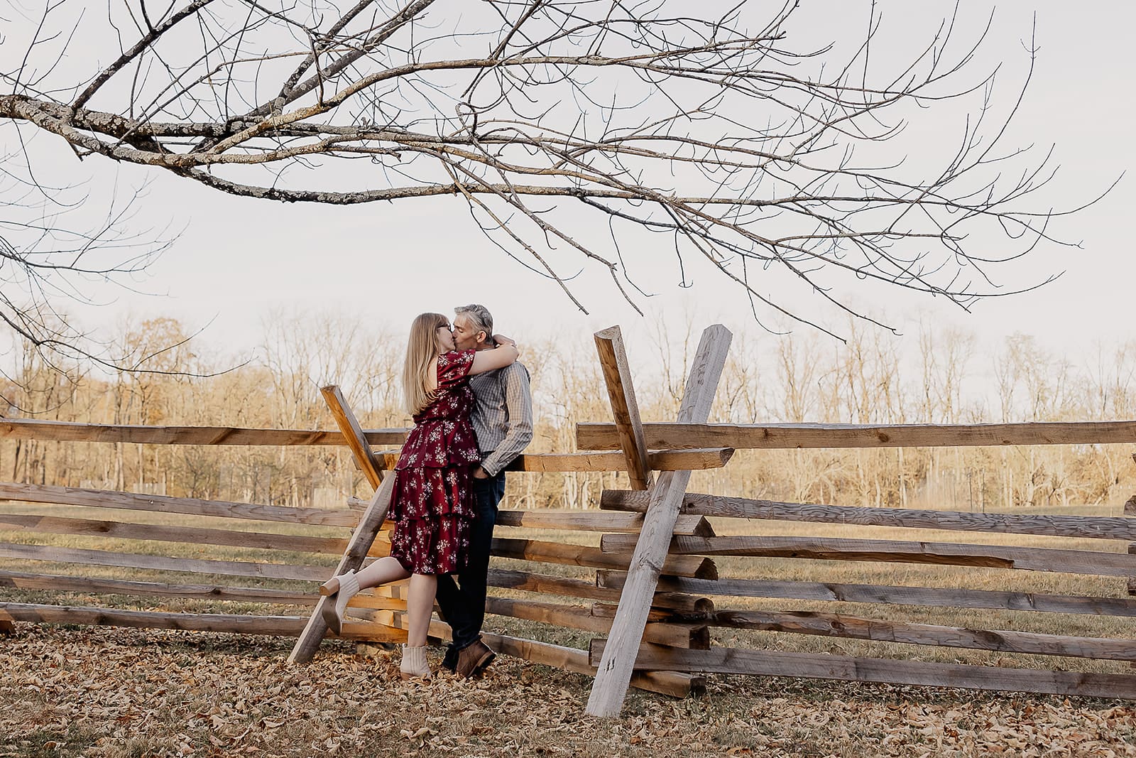 Couple kissing against a fence for their NJ engagement photos at at Jockey Hollow in Morristown.