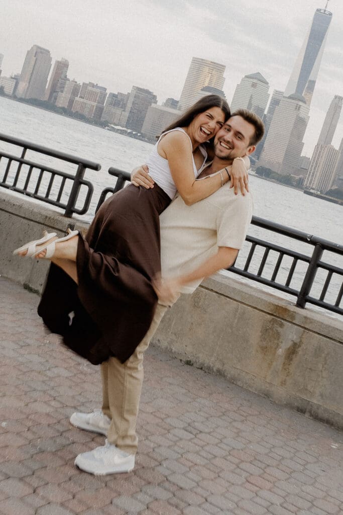 Candid photo of a couple laughing during their waterfront Liberty State Park engagement photos in Jersey City, NJ.