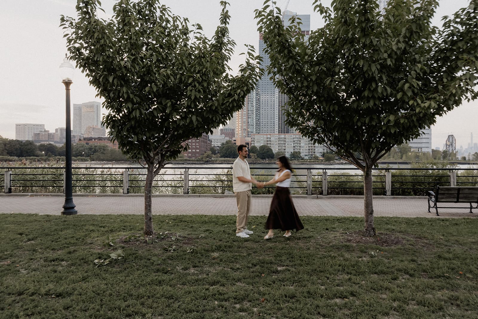 Motion blur photo of a couple holding hands in a grassy area for their Liberty State Park engagement photos in Jersey City, NJ.