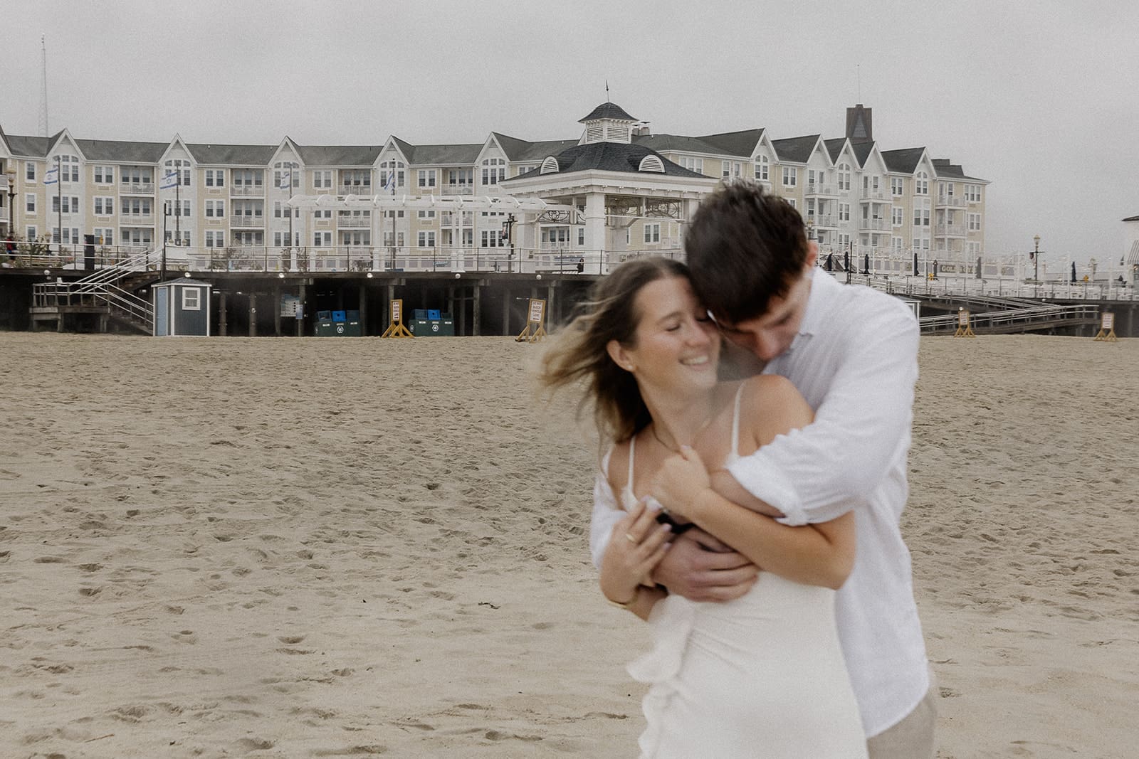 Couple hugging on the beach in Long Branch NJ for their engagement photos.