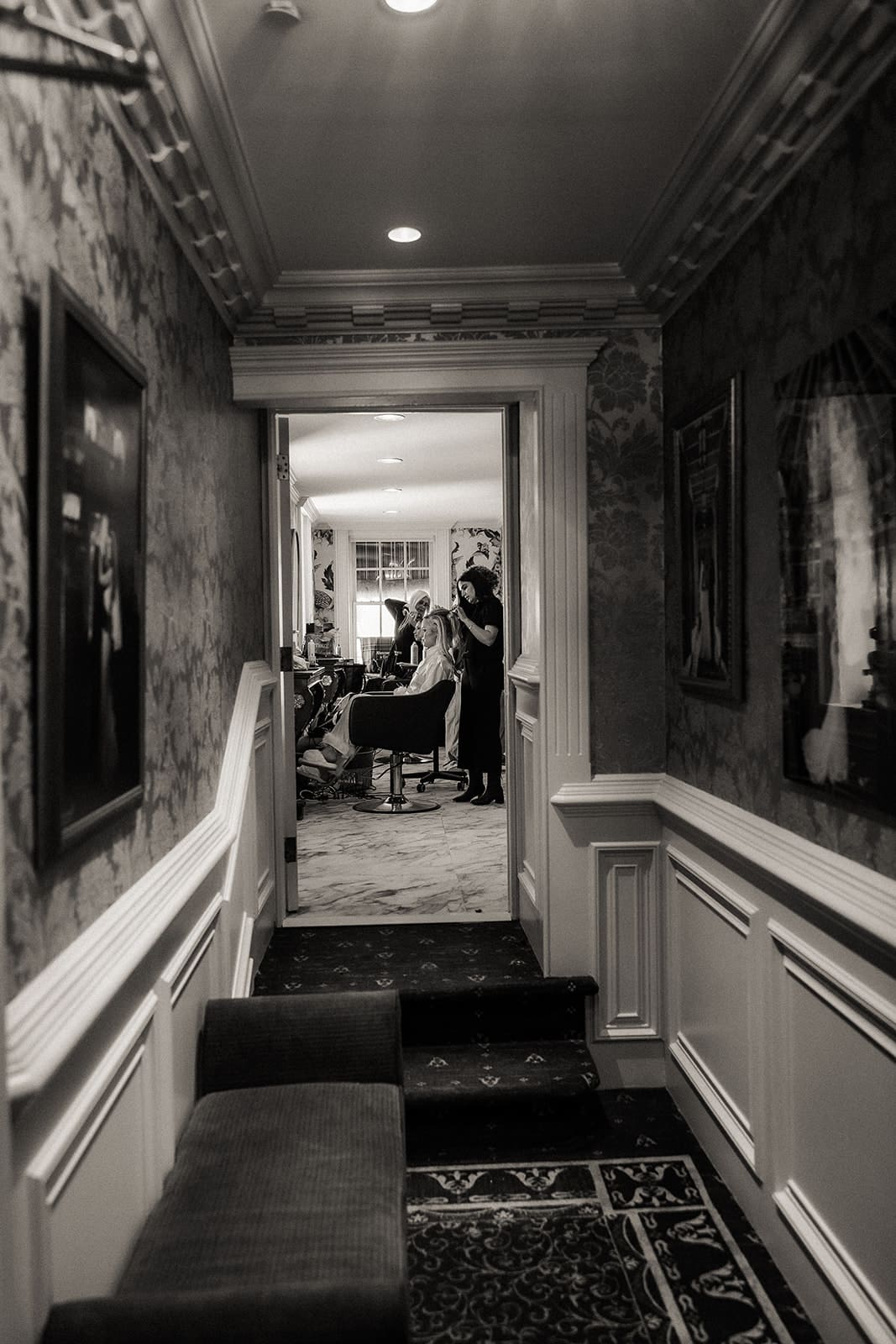 Candid black and white photo of a bride getting her hair done at Brides dress hanging on the wall at The Brownstone in Paterson, NJ.
