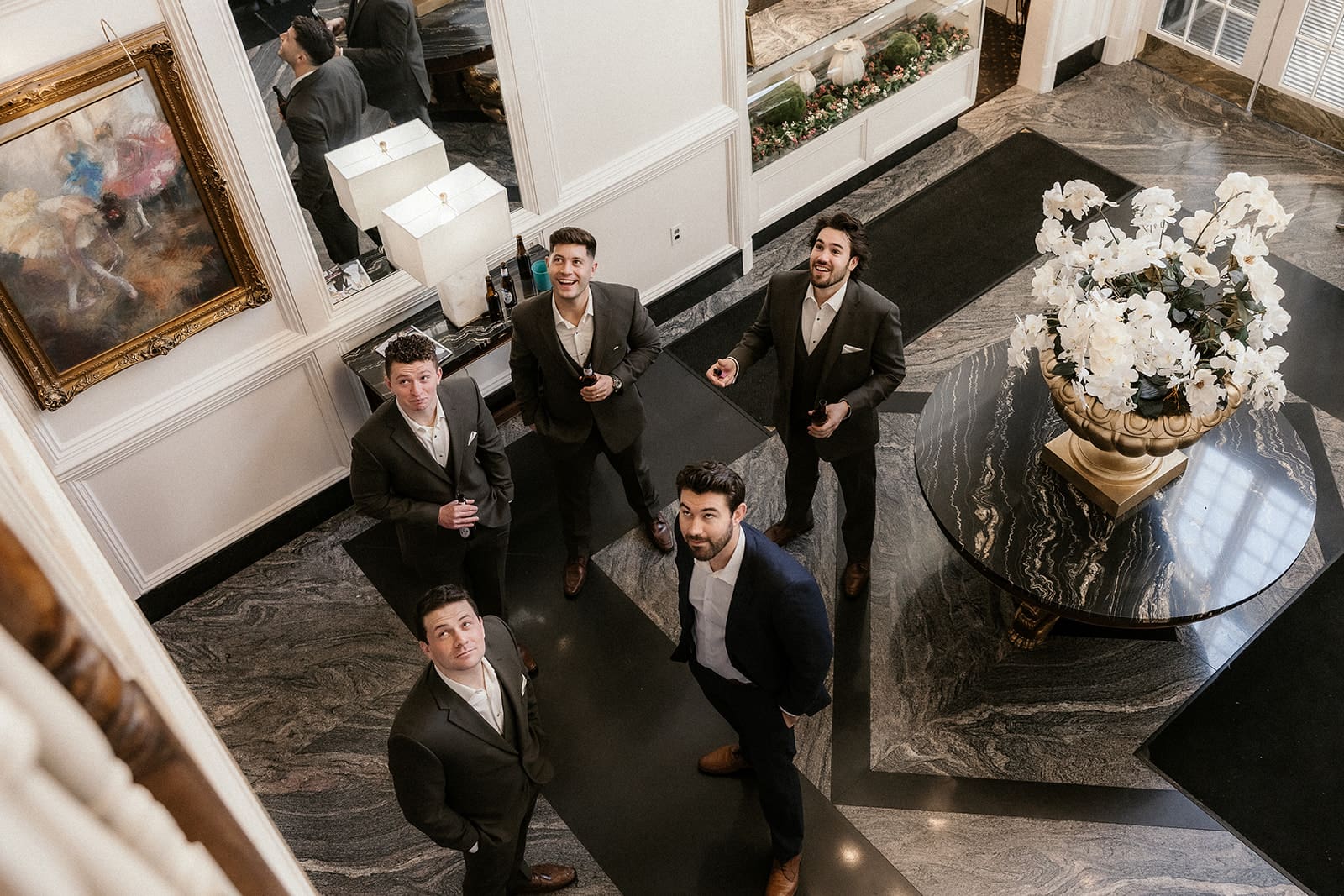 Groomsmen looking up at the balcony while the bride and groom take portraits.