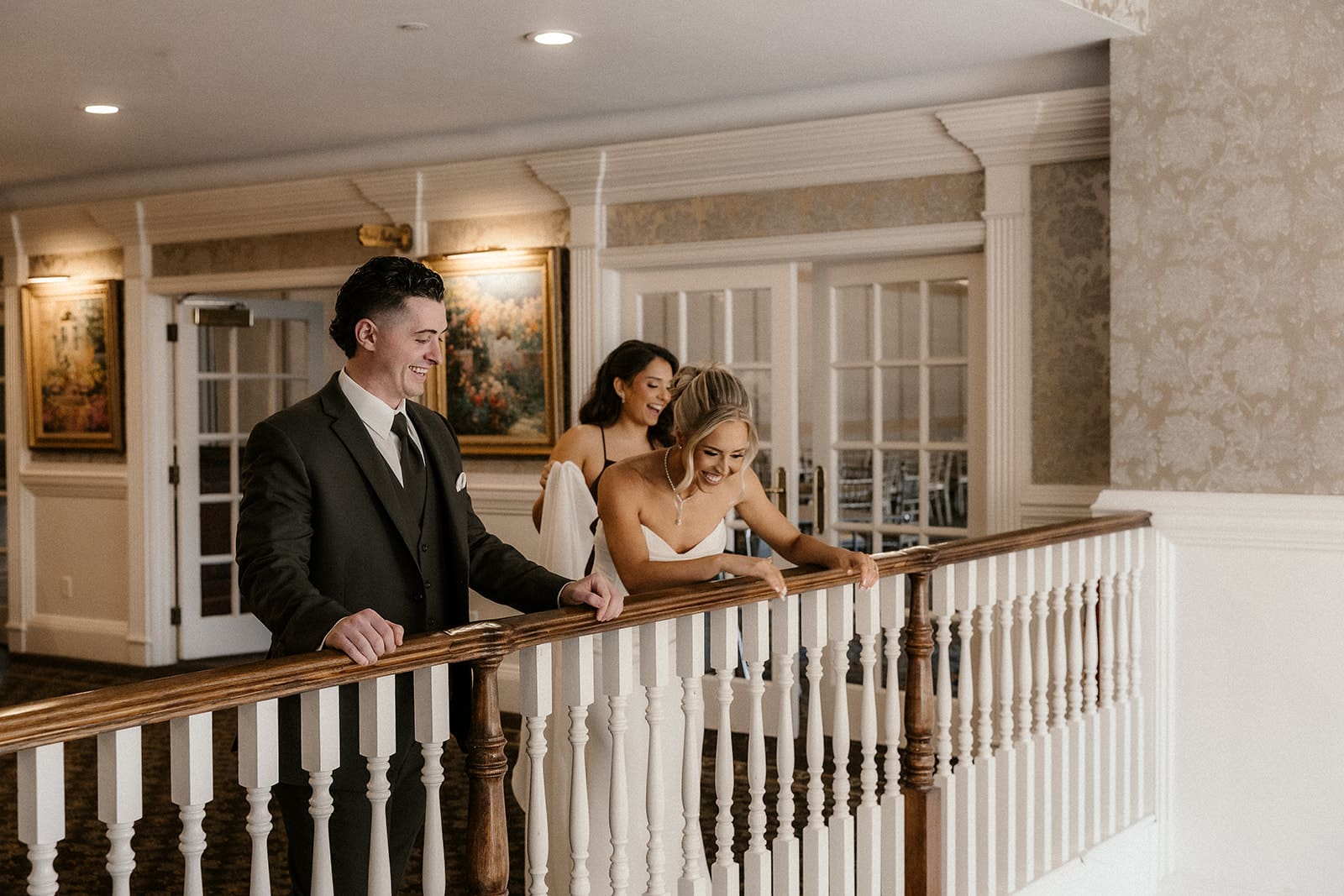 Bride and groom looking over the balcony at the groomsmen.