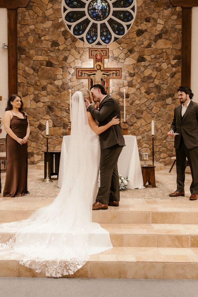 Bride and groom sharing their first kiss during a Catholic wedding ceremony at St. Mary’s Church in Pompton Lakes, NJ.