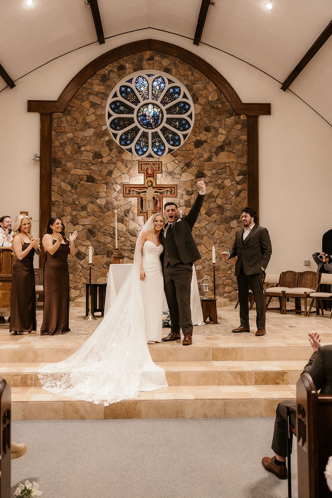 Bride and groom raising their hands in celebration after their ceremony at St. Mary’s Church in Pompton Lakes, NJ.