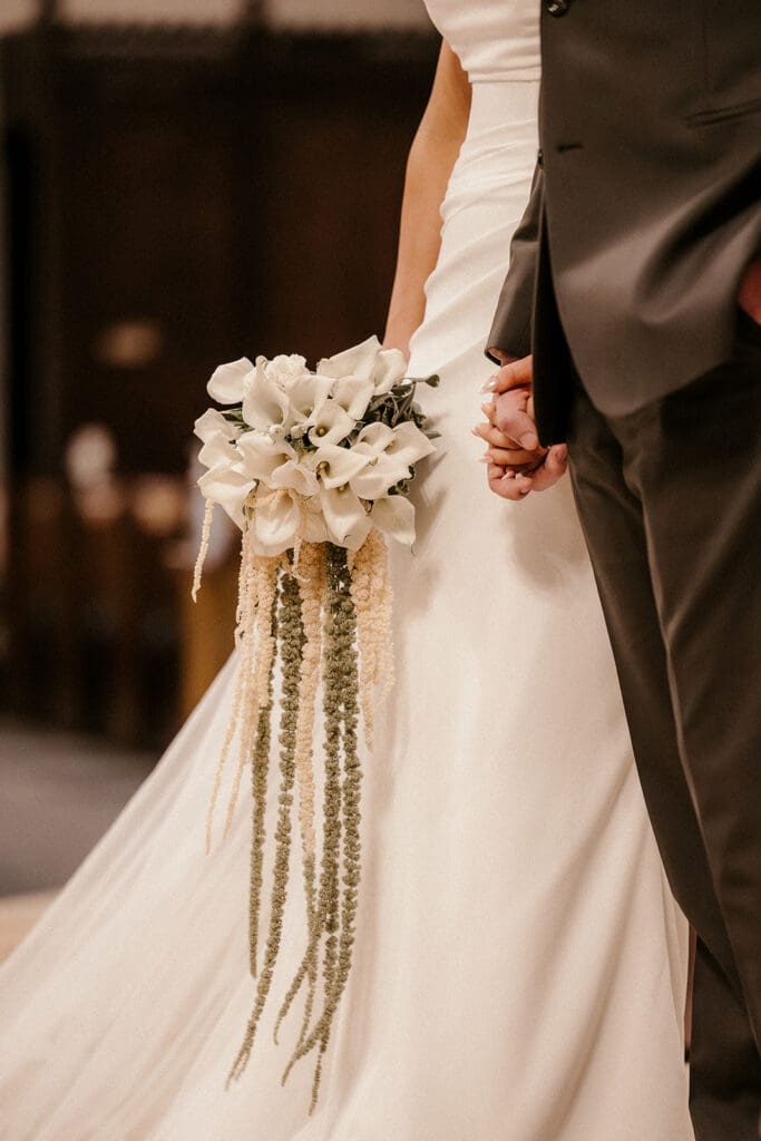 Bride holding her bouquet and groom’s hand during their ceremony at St. Mary’s Church in Pompton Lakes, NJ.

