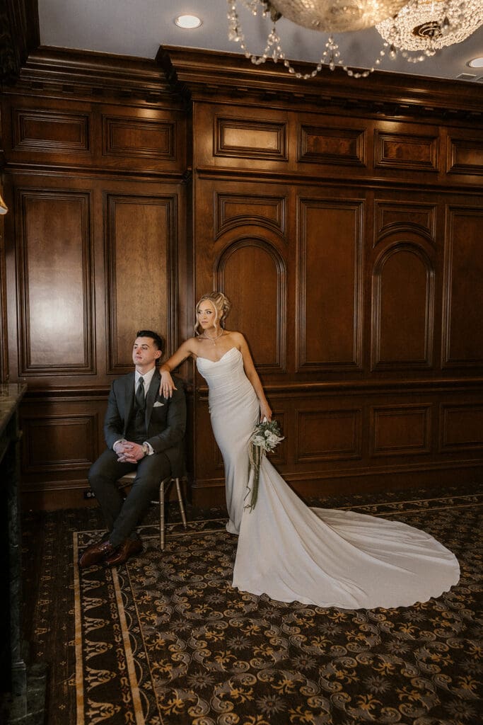 Editorial photo of a bride and groom posing in a wood-paneled room during their wedding at The Brownstone in Paterson, NJ.