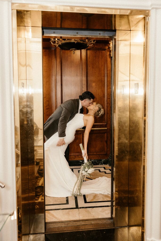 Bride and groom kissing behind the gold elevator doors at The Brownstone in Paterson, NJ.