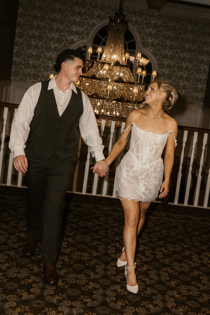 Bride and groom walking hand in hand after their reception outfit change at The Brownstone in Paterson, NJ.