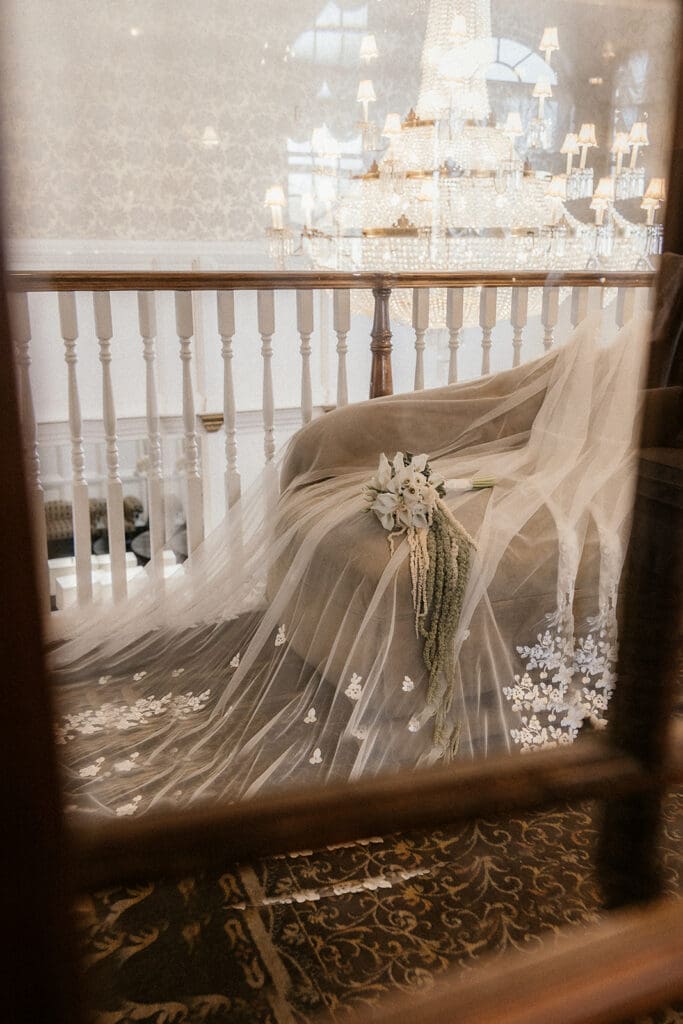 Bride veil and flowers styled on a chair at Brides dress hanging on the wall at The Brownstone in Paterson, NJ.