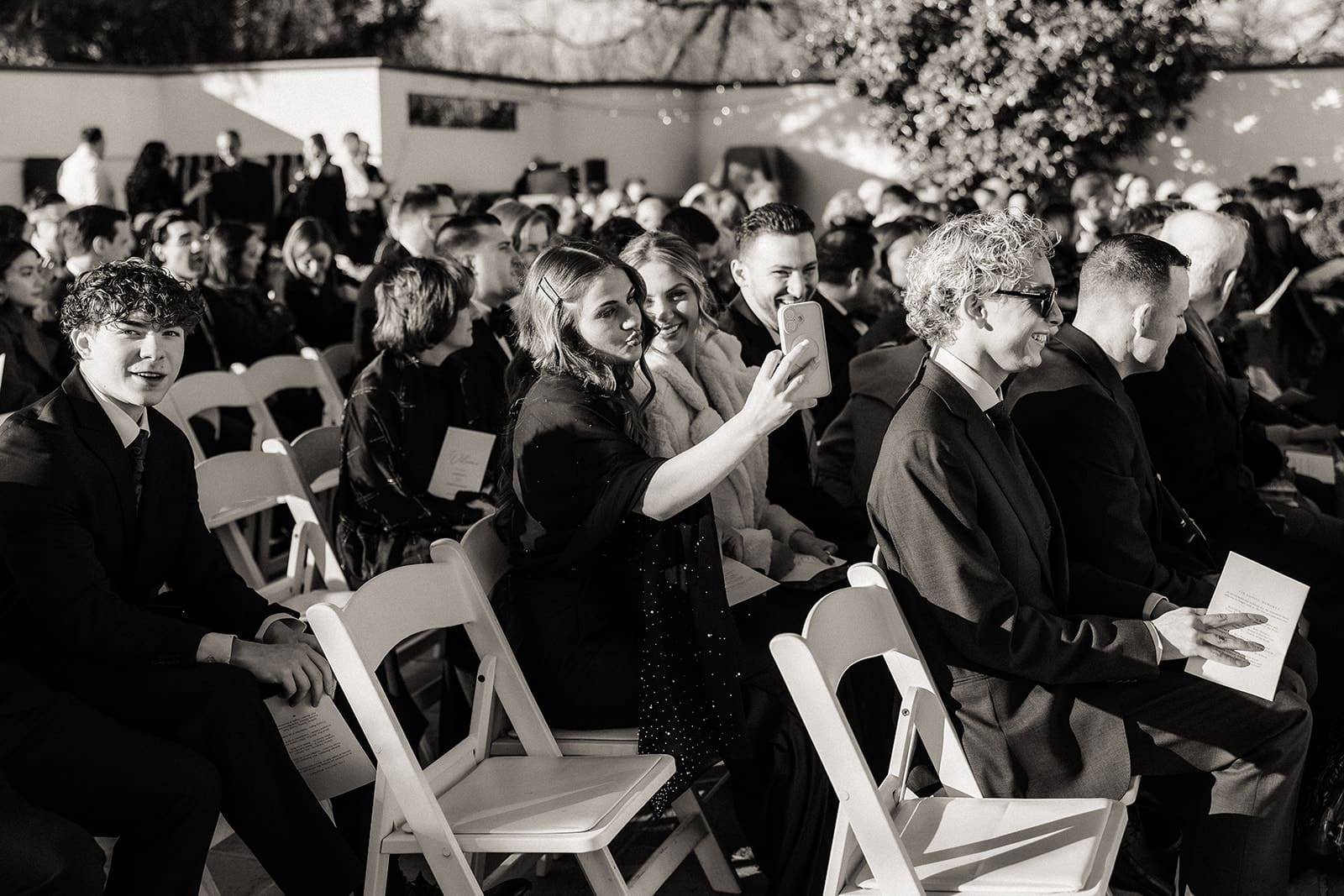 Black and white candid shot of guests waiting for the wedding ceremony to start.