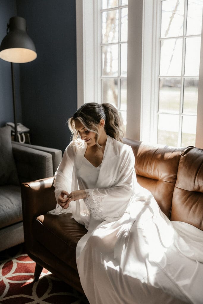 Bride sitting on a couch and admiring her wedding rings.