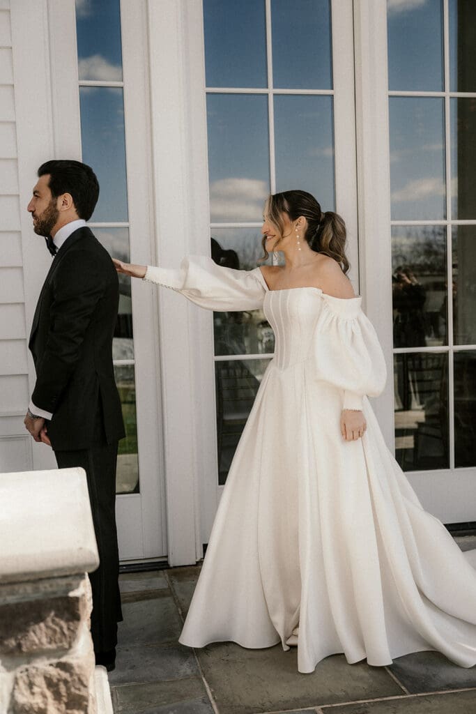 Bride tapping the groom on the shoulder during their first look.
