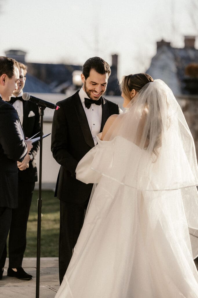 Bride and groom smiling during their outdoor wedding ceremony at The Ryland Inn.